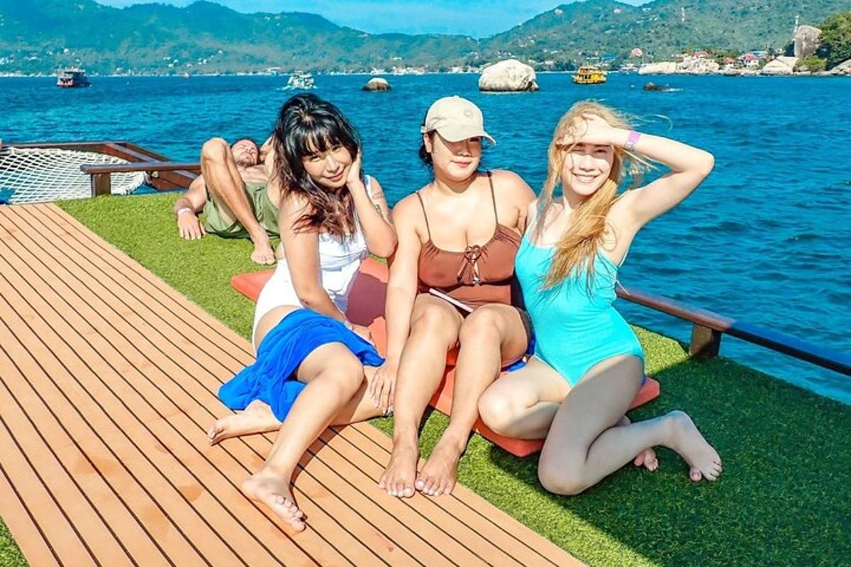 three women sitting on a deck next to the water