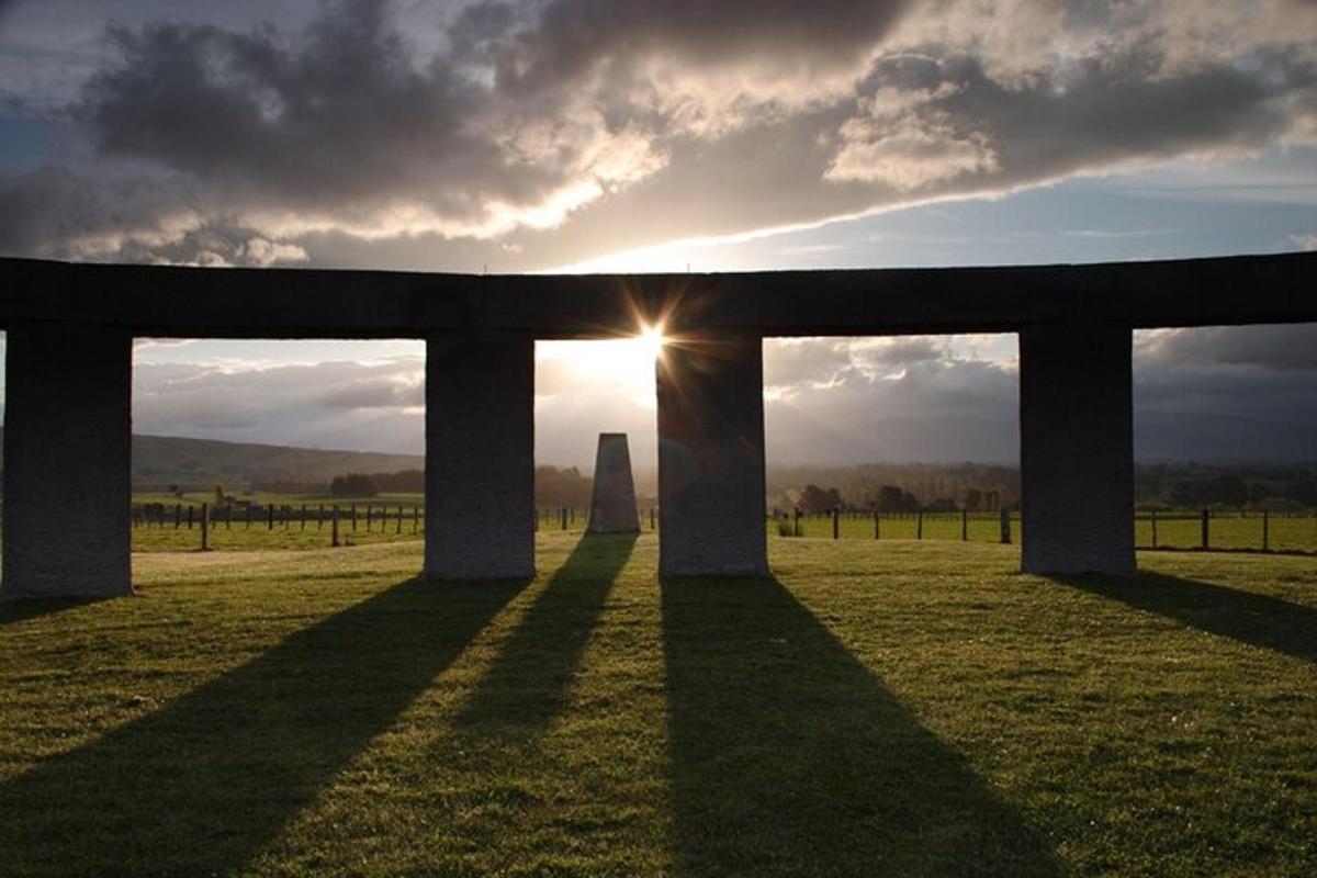 an obelisk in a field with the sun shining through