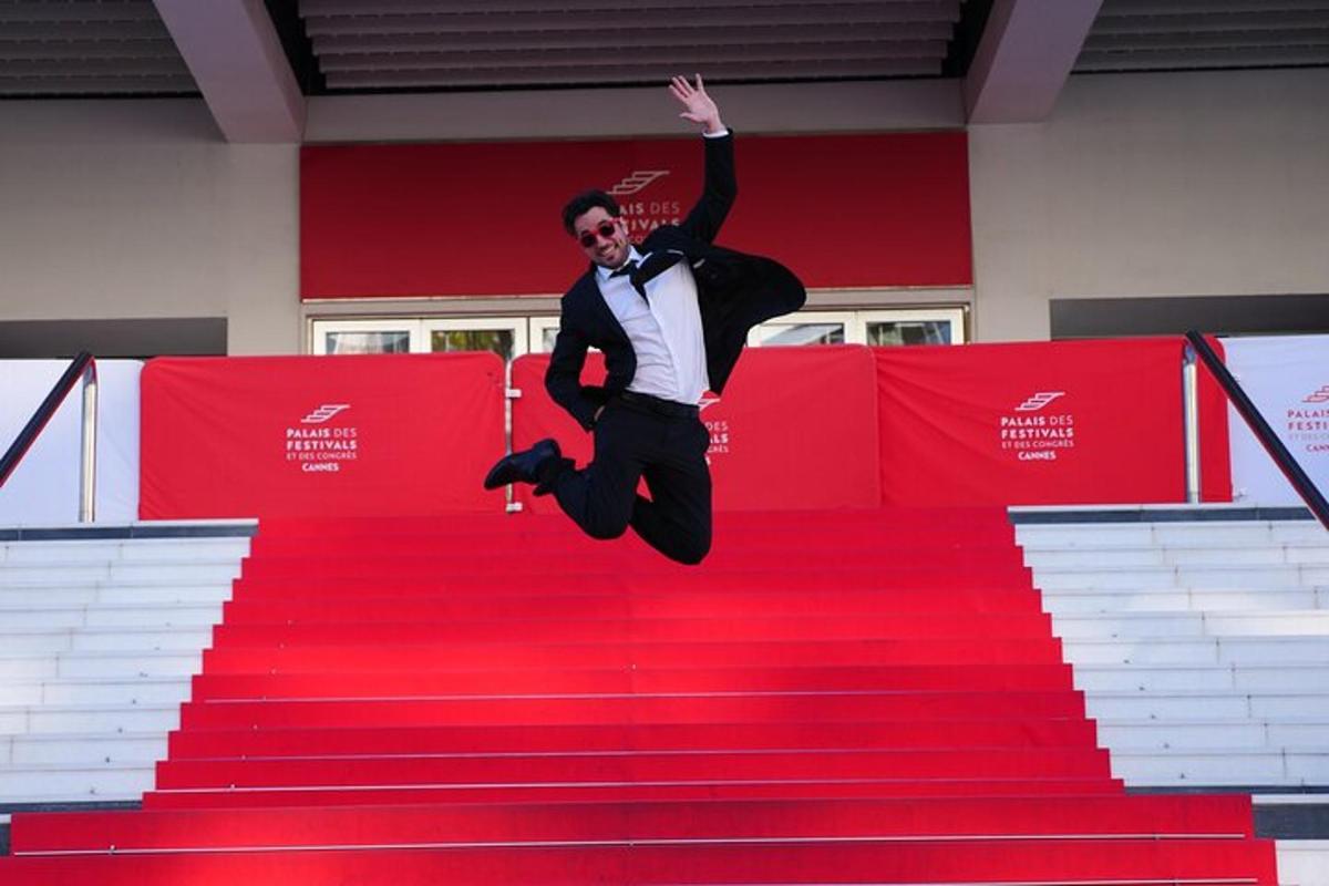 a man in a tuxedo jumping on a red carpet