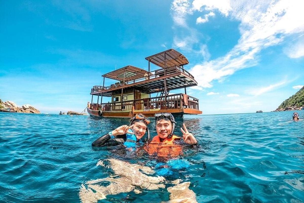 một người đàn ông và một người phụ nữ ở dưới nước trước một chiếc thuyền