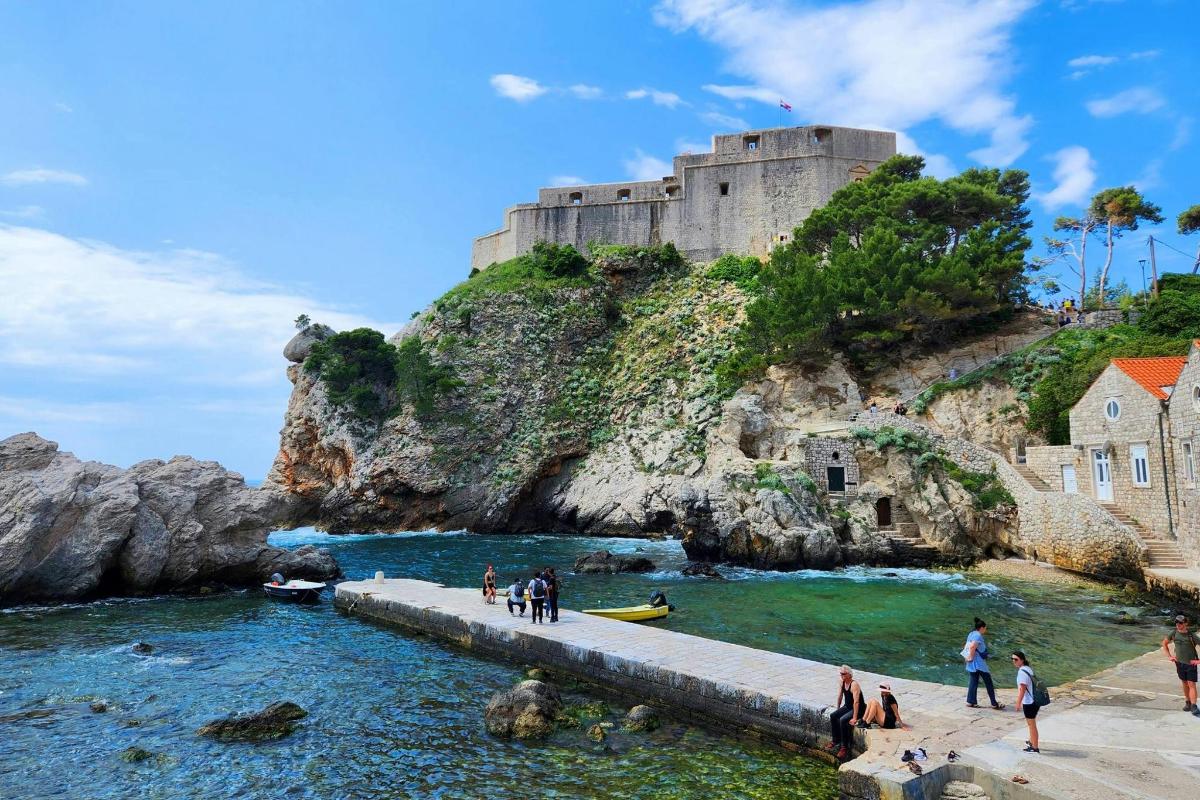 un gruppo di persone in piedi su un molo di fronte a un castello