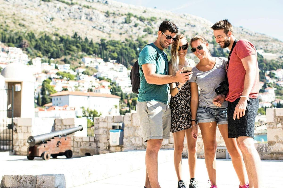 tre persone in piedi una accanto all'altra che guardano un cellulare