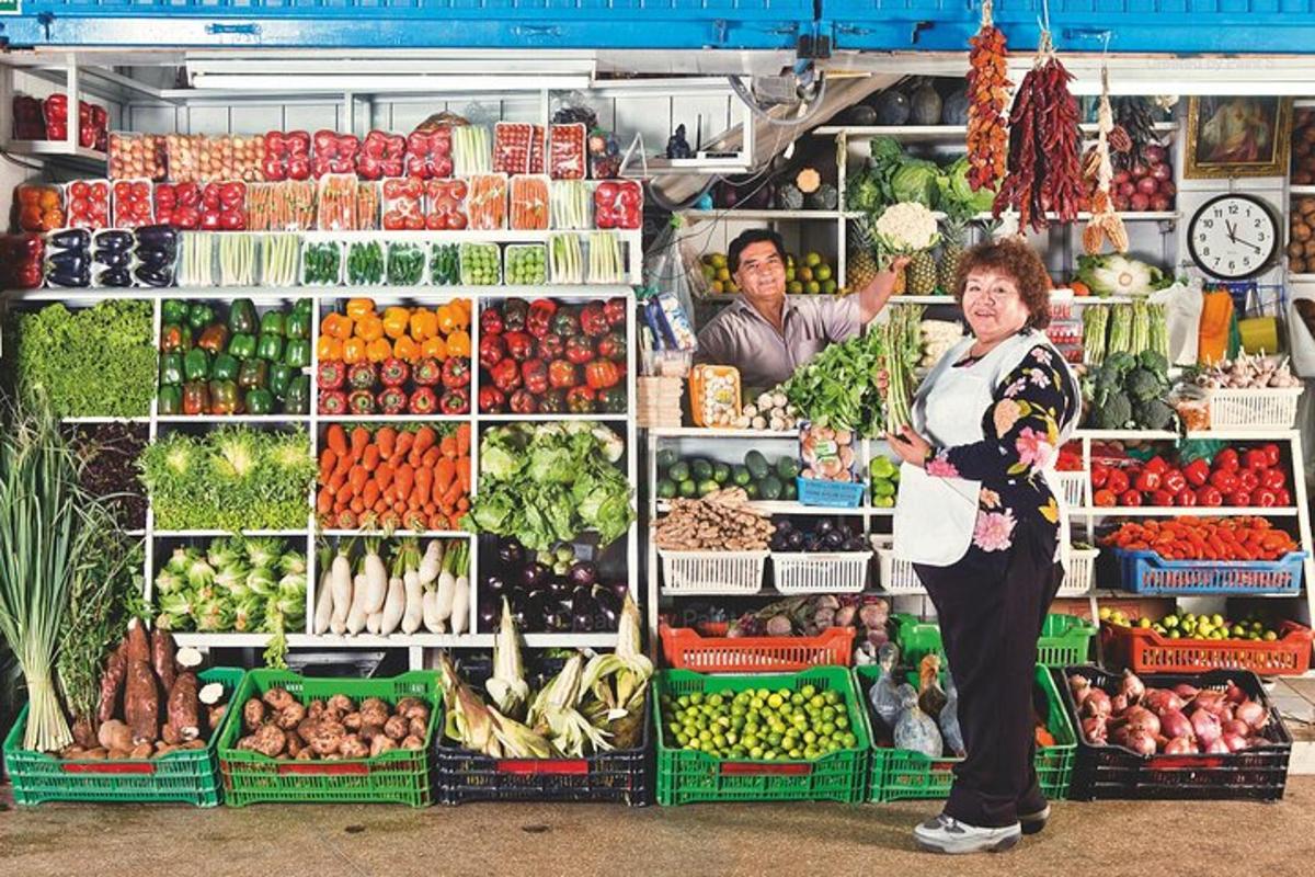 una dona dreta davant d'una parada de productes frescos