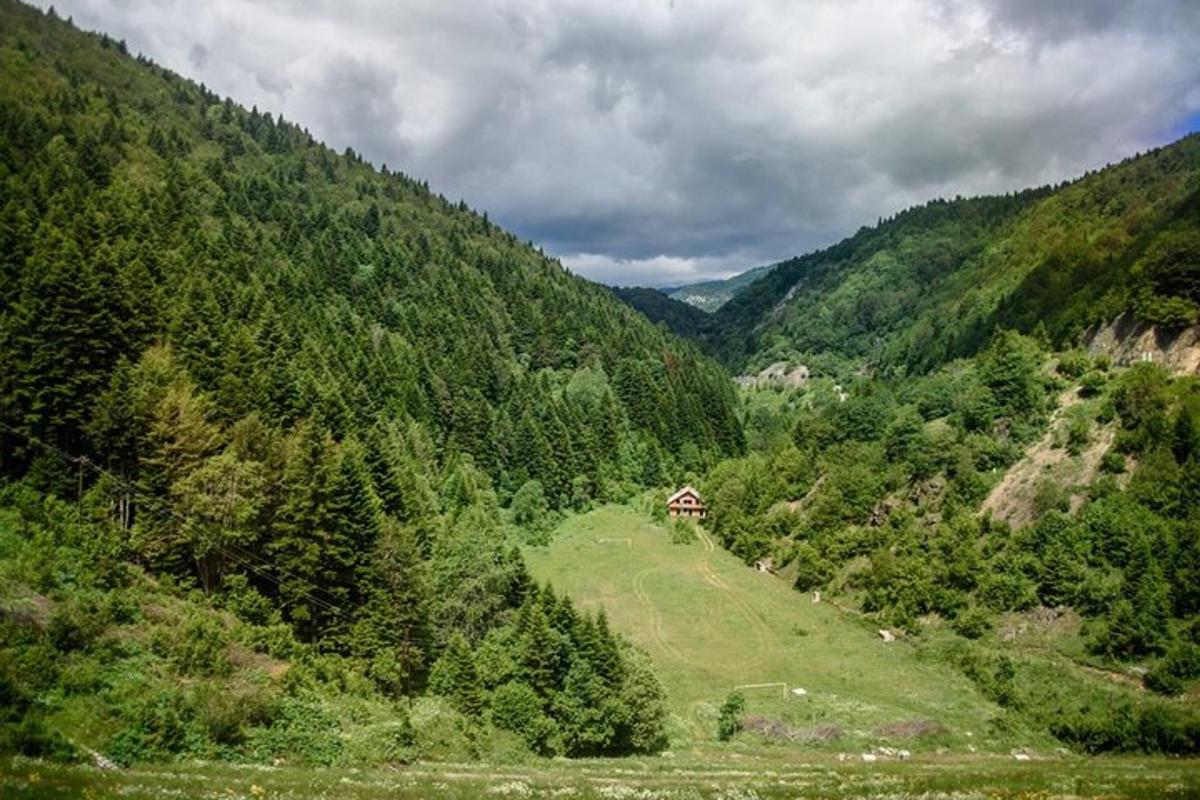 a green valley with a house on the side of a hill