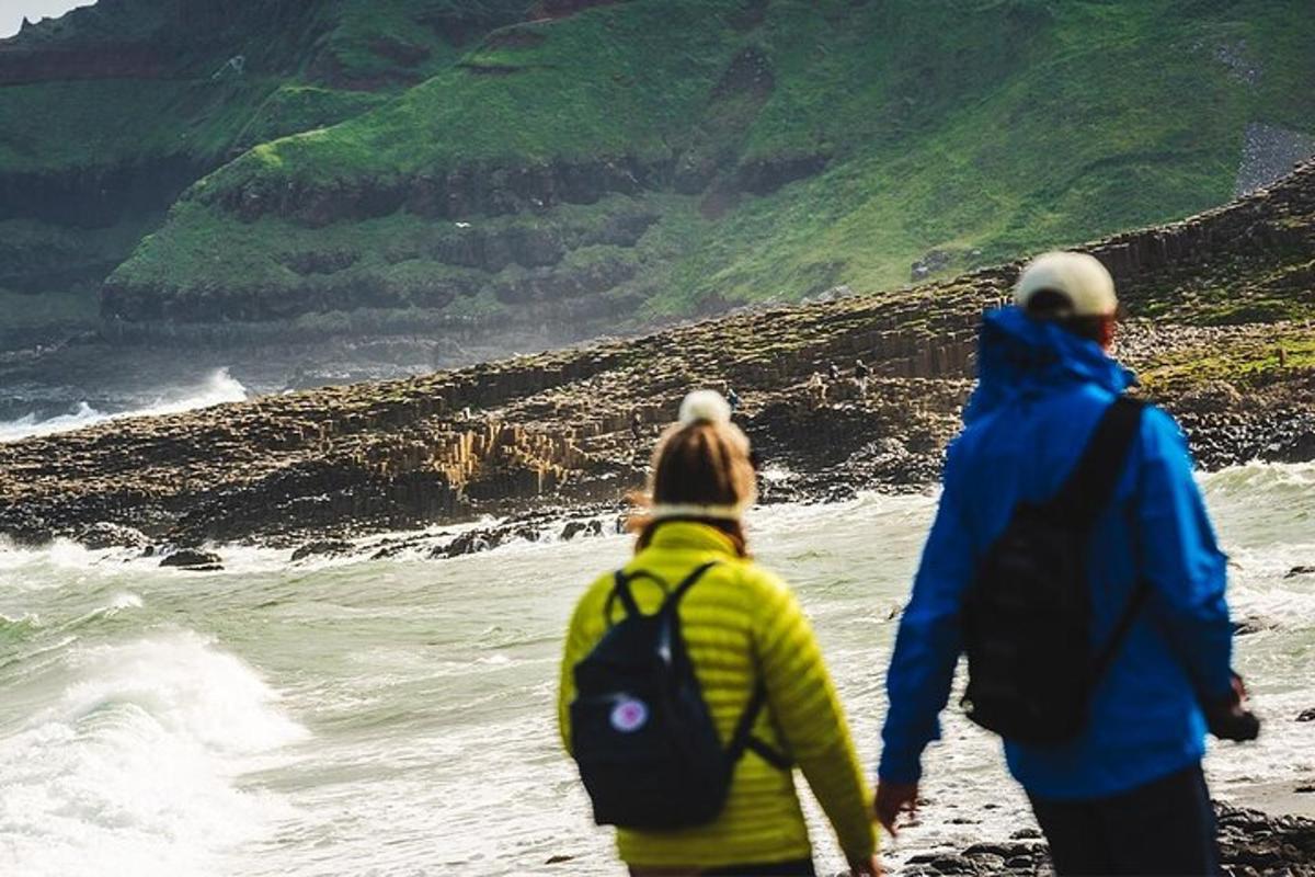 two people walking on the beach looking at the water