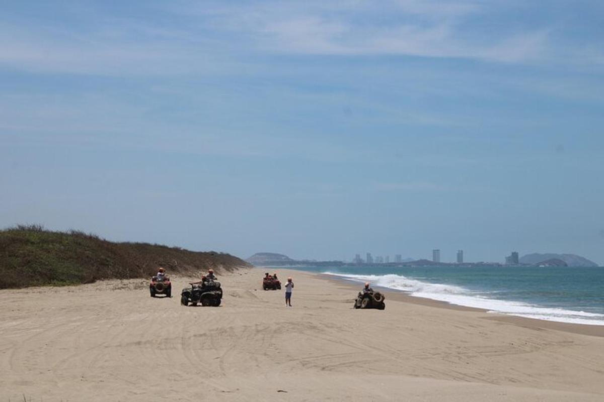 un grup de persones anant amb quads a la platja