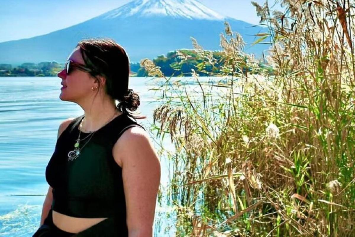 žena stojící u vody s horou v pozadí