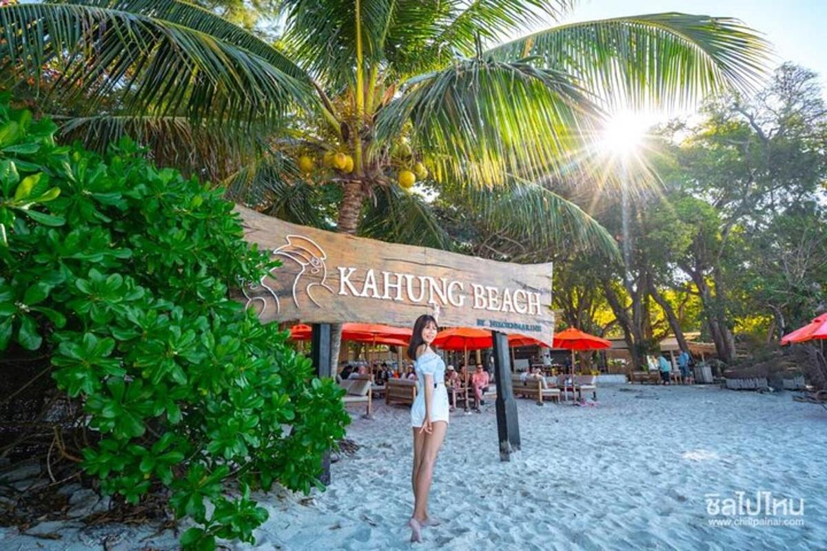 seorang wanita berdiri di pantai di hadapan sebuah restoran