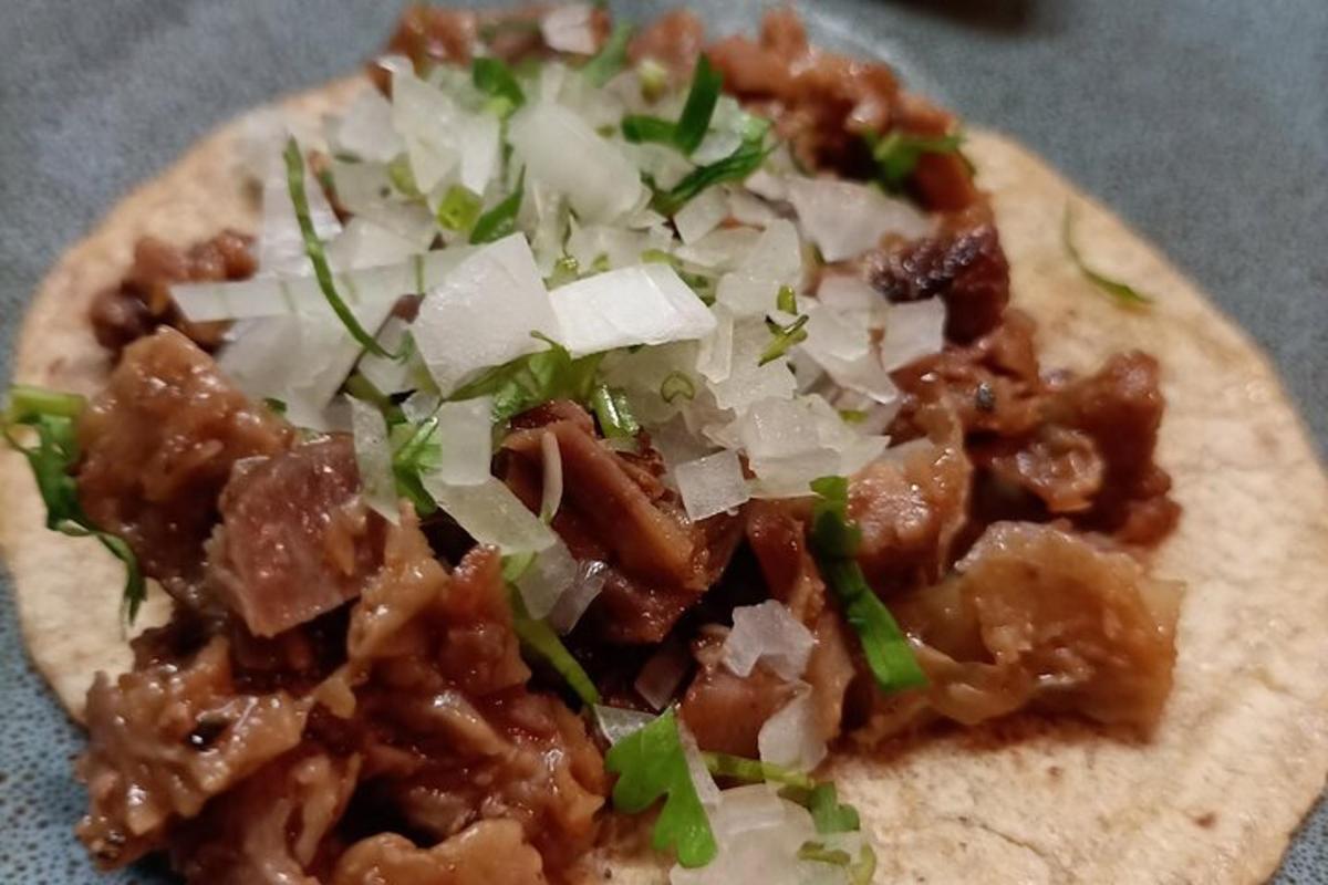 eine Tortilla-Pizza mit Fleisch und Zwiebeln darauf