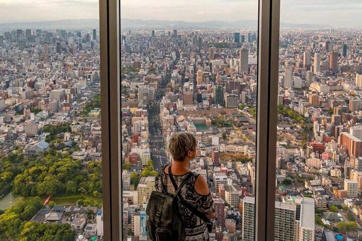 a woman standing in front of a window looking at a city