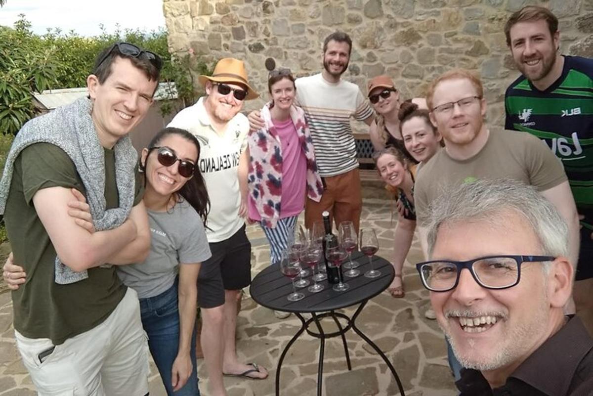 un gruppo di persone in piedi attorno a un tavolo con bicchieri di vino
