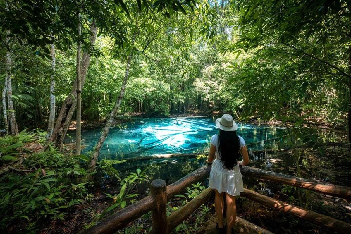 una donna con un cappello in piedi su una recinzione vicino a un fiume