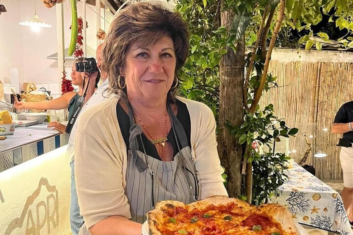 žena sedící u stolu s pizzou