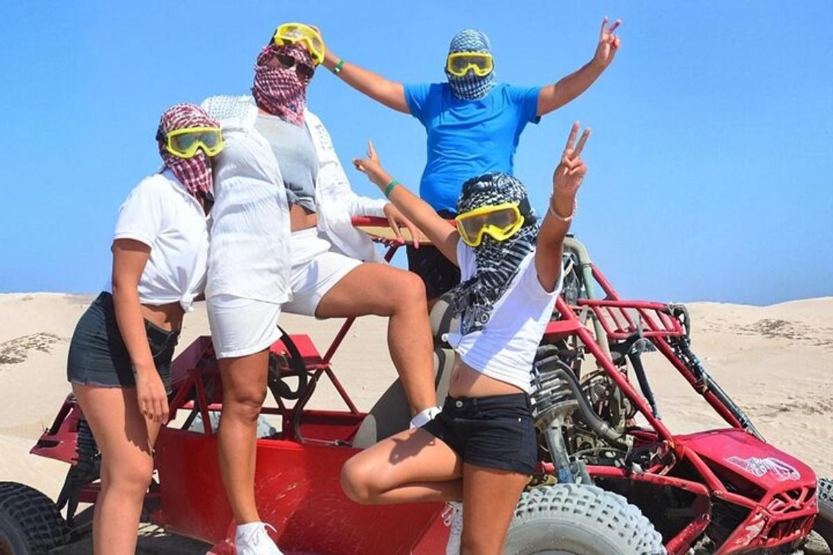 sekumpulan orang duduk di atas trak di dalam pasir