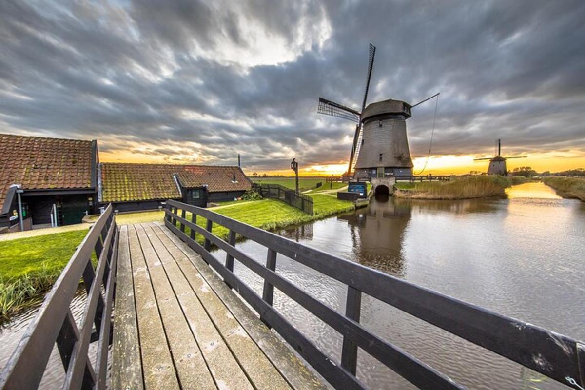 Un puente de madera con un molino de viento junto a un río.