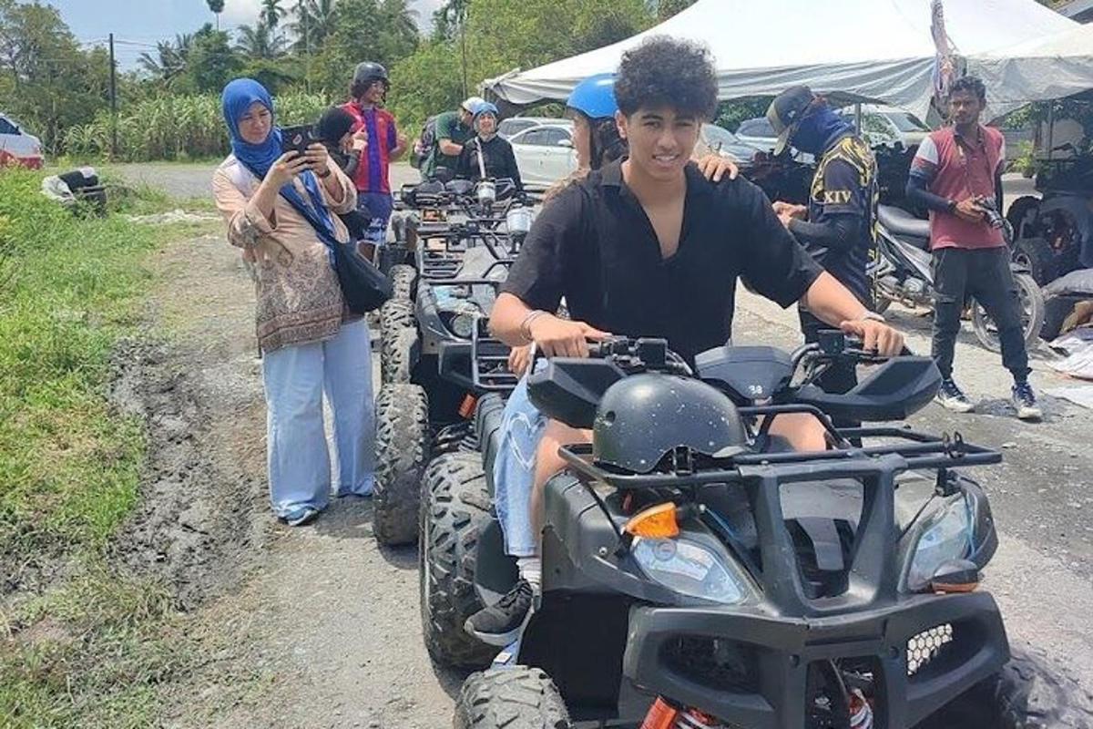 um homem sentado em um quadriciclo em uma estrada de terra