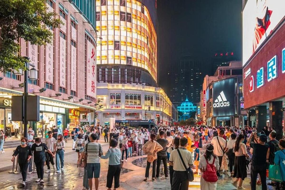 a crowd of people crossing a busy city street at night