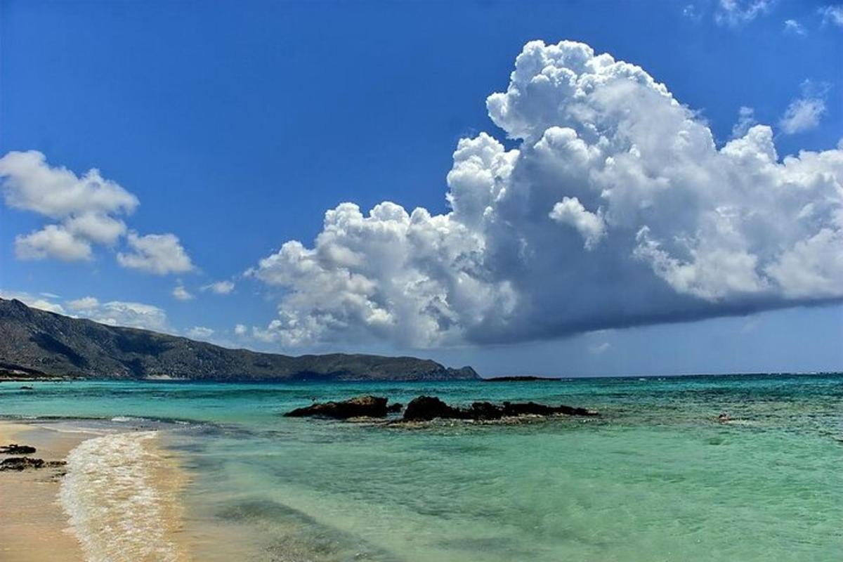 una vista di una spiaggia con acqua blu e nuvole