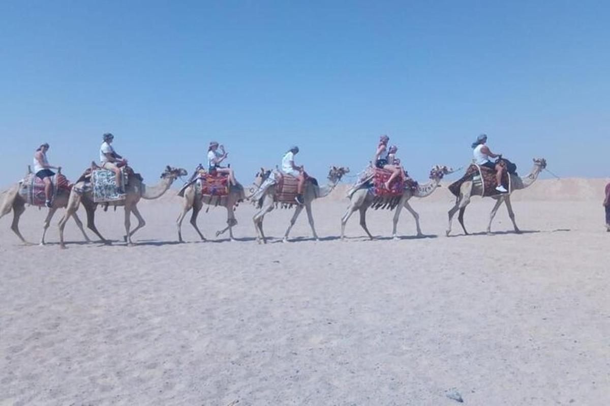 un gruppo di persone a cavallo di cammelli nel deserto