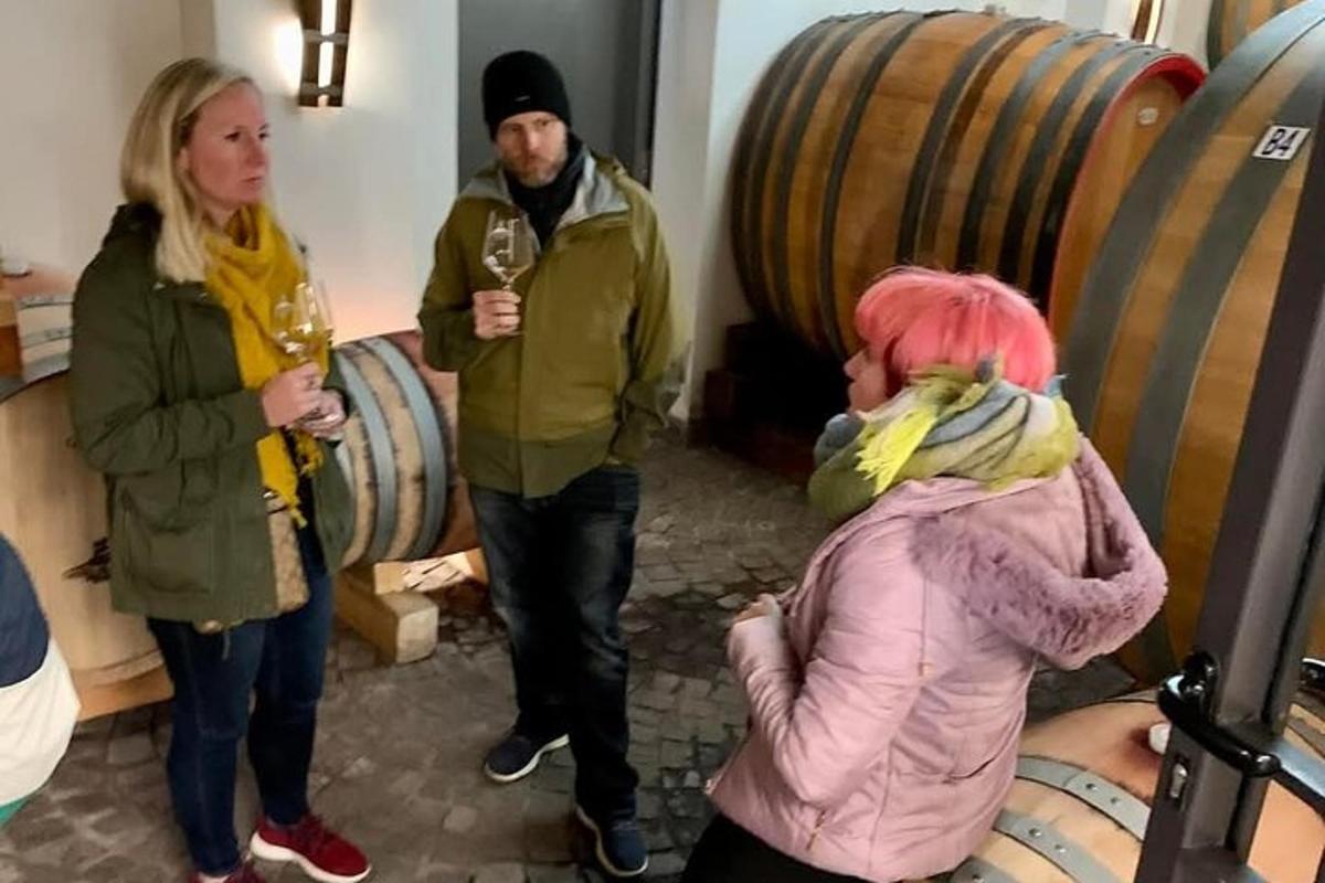 un uomo e due donne in piedi in una stanza con dei bicchieri di vino