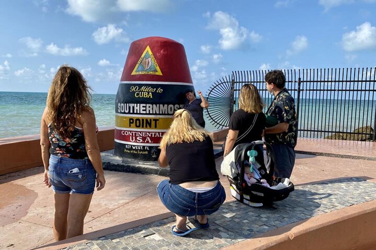 un grup de persones dempeus al voltant d'un rètol prop de l'oceà