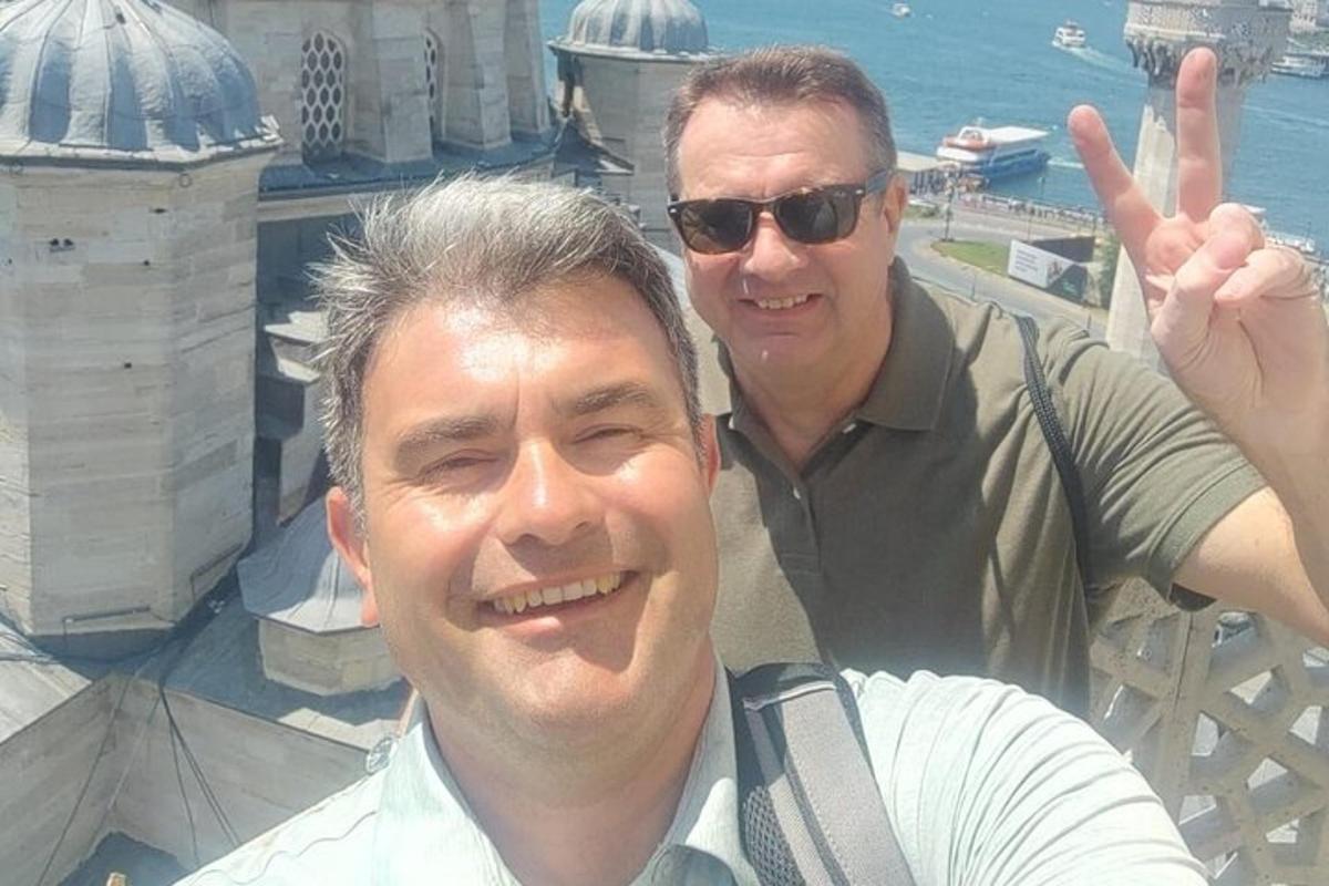 two men posing for a picture with their hand in the air