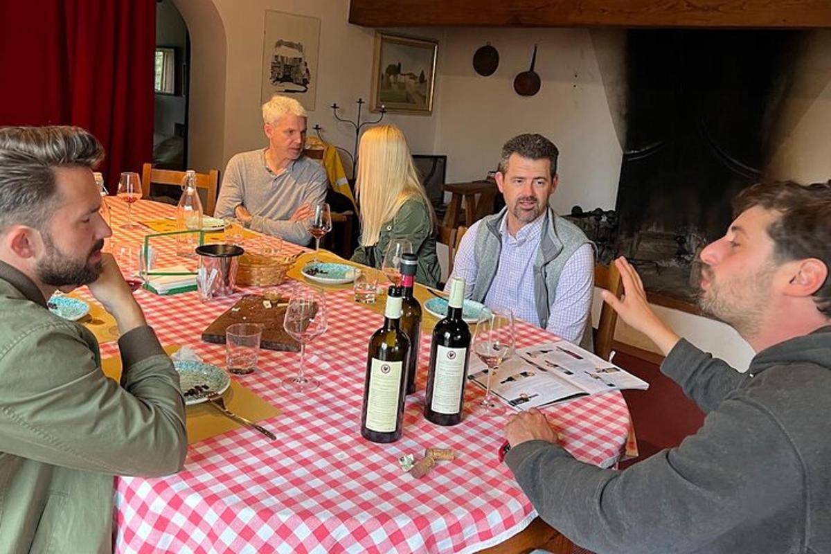un grup de oameni așezați în jurul unei mese cu sticle de vin