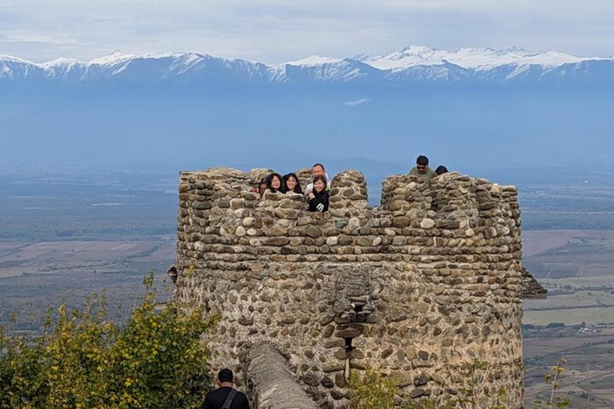 μια ομάδα ανθρώπων που κάθονται πάνω σε έναν πέτρινο τοίχο