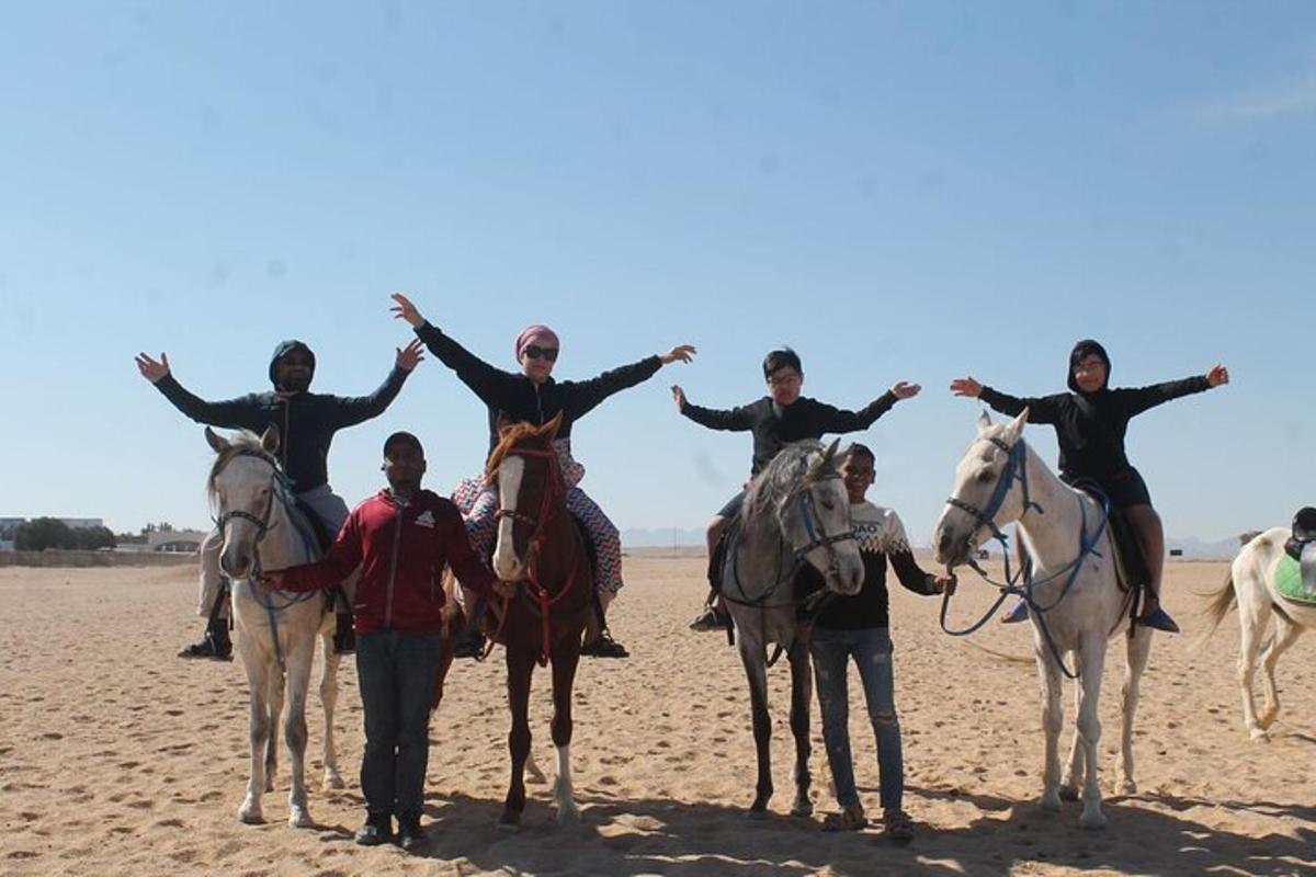 um grupo de pessoas andando a cavalo na praia
