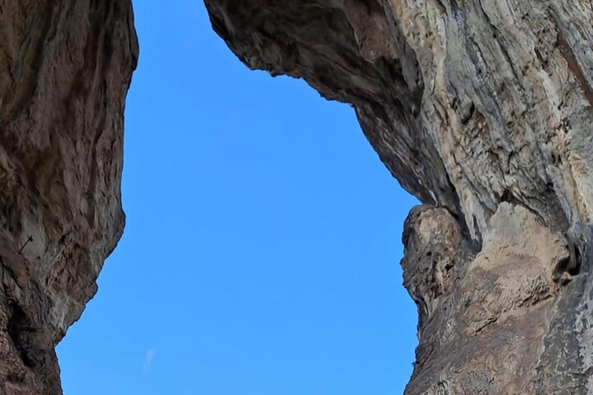 okno ve skalním útvaru s modrou oblohou