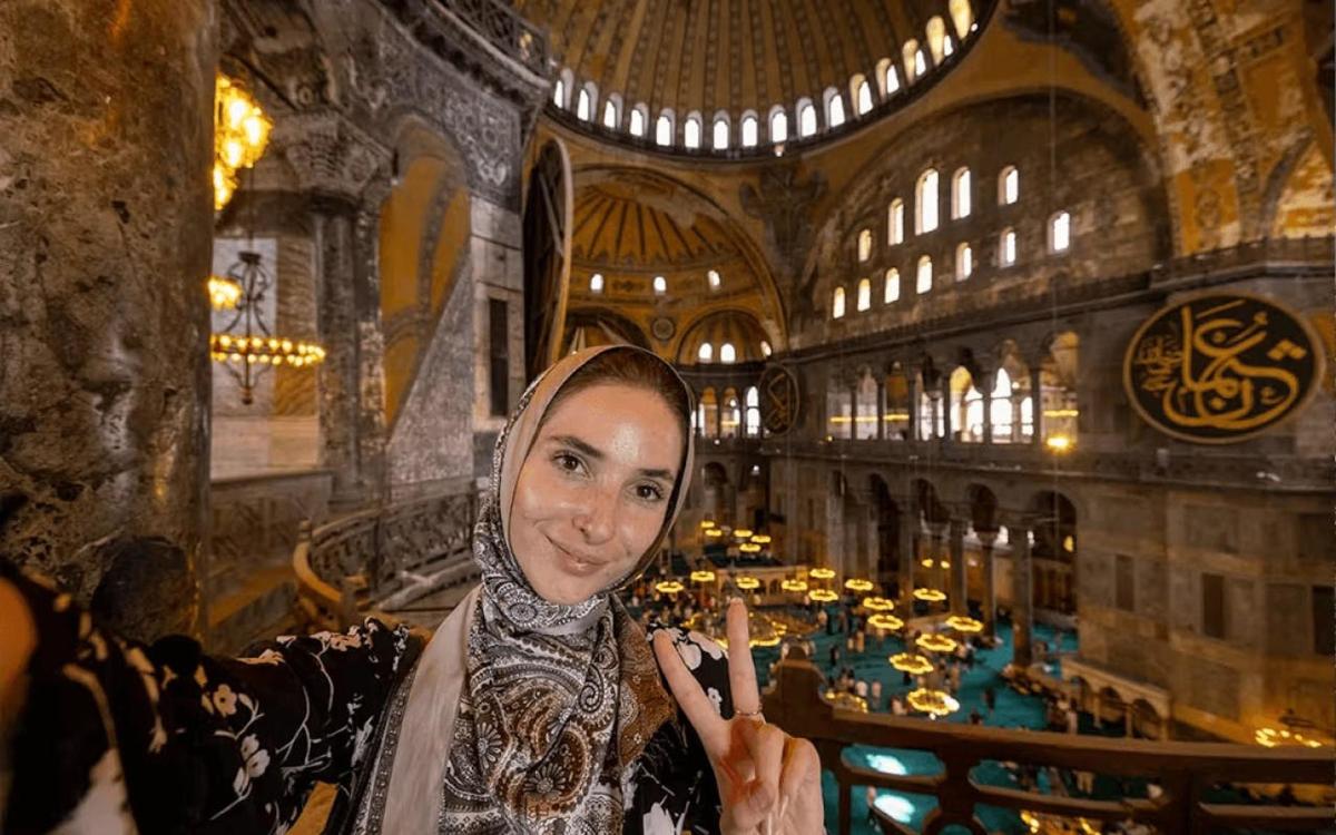 egy nő áll egy épületben a kezében mobiltelefonnal