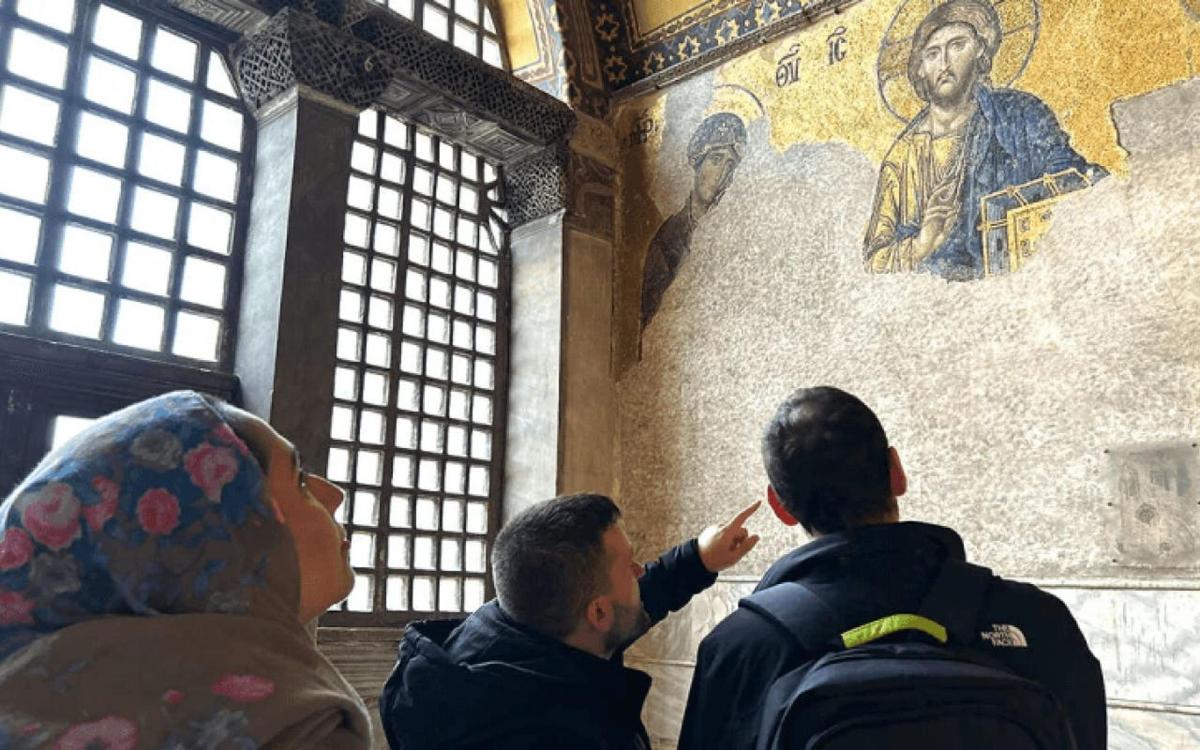 egy csoport ember néz egy festményt a falon