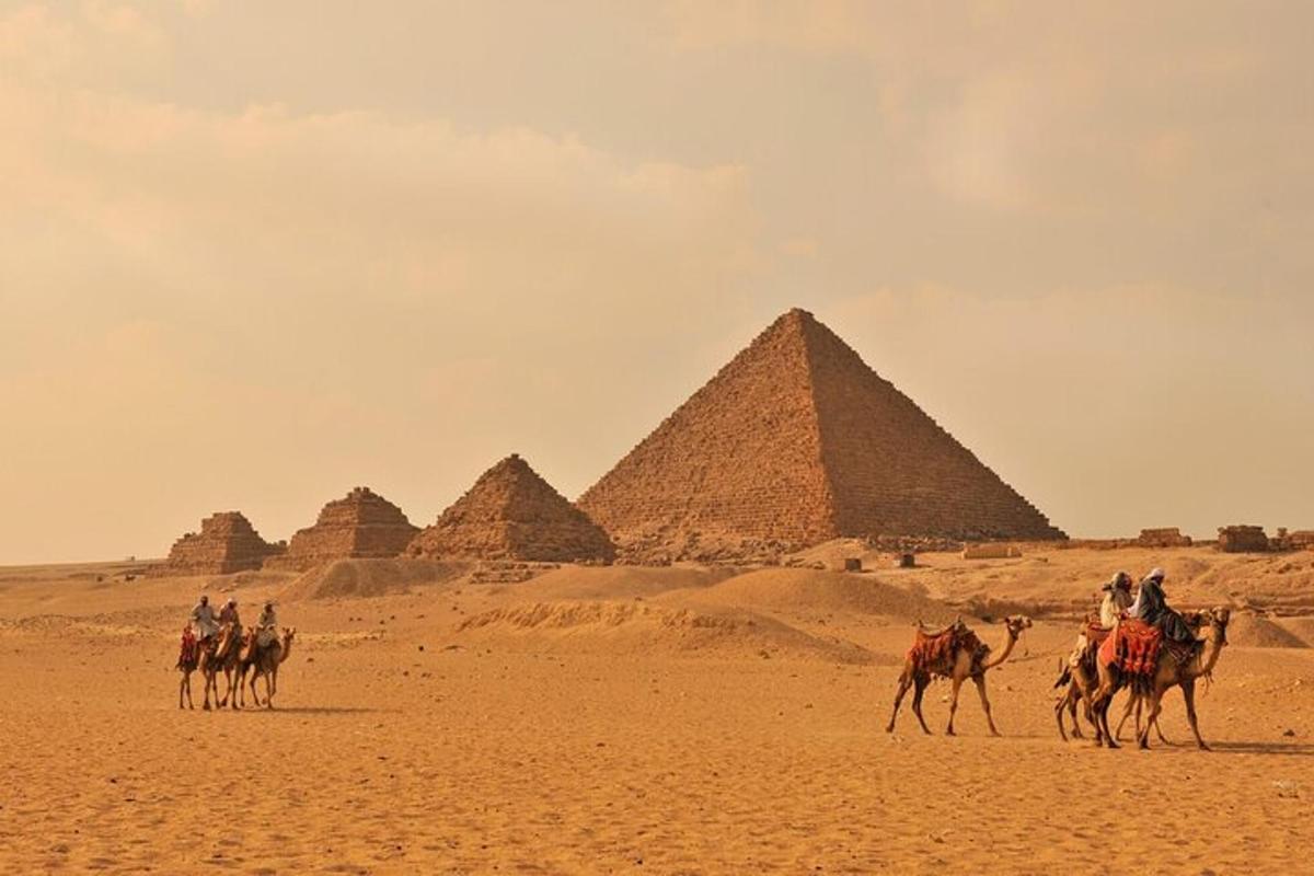 Skupina lidí na koních před pyramidami