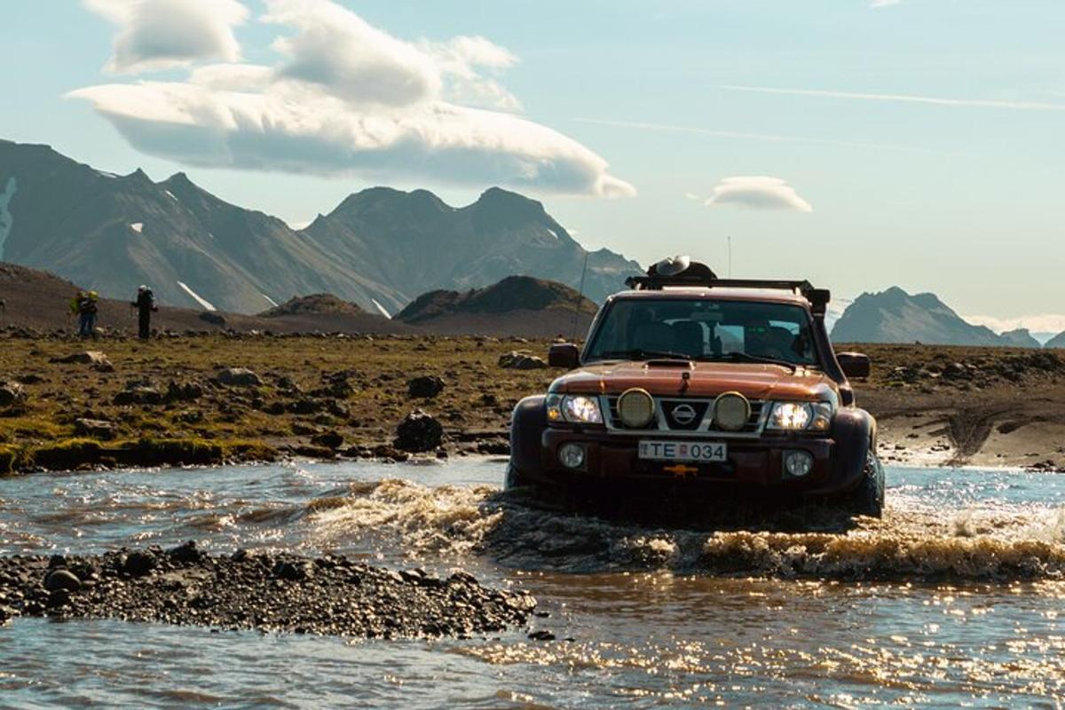 một chiếc xe jeep đang chạy qua một con sông ở sa mạc