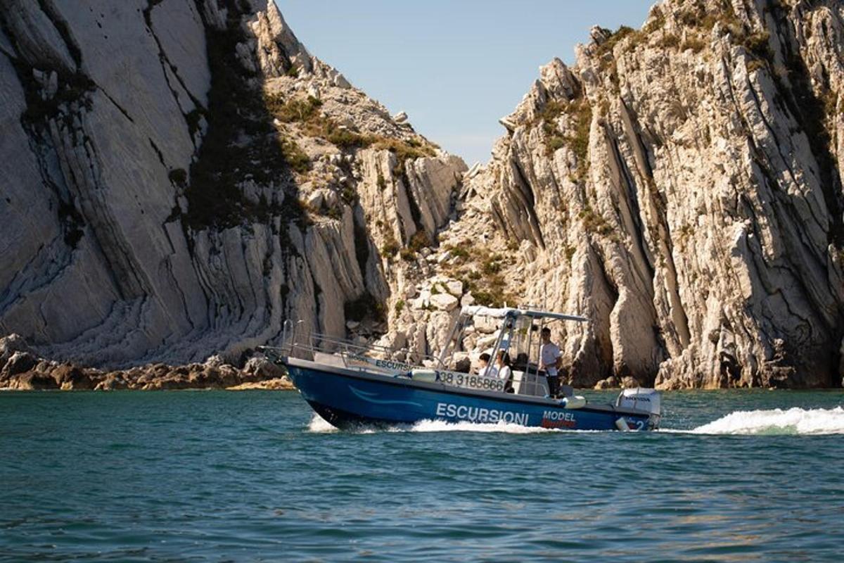 a blue boat in the water next to a cliff