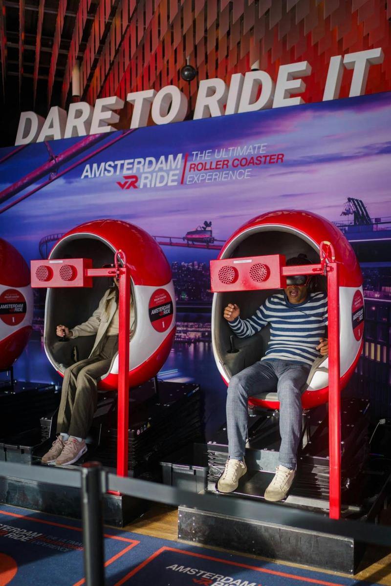 Dos personas sentadas en sillas rojas en un escenario.