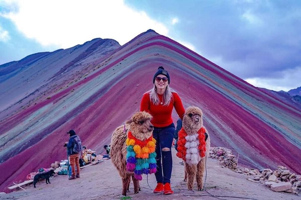 a woman standing next to two poodles in front of a mountain