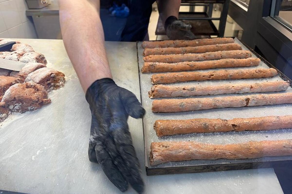 en person i sorte handsker, der laver hotdogs på en grill