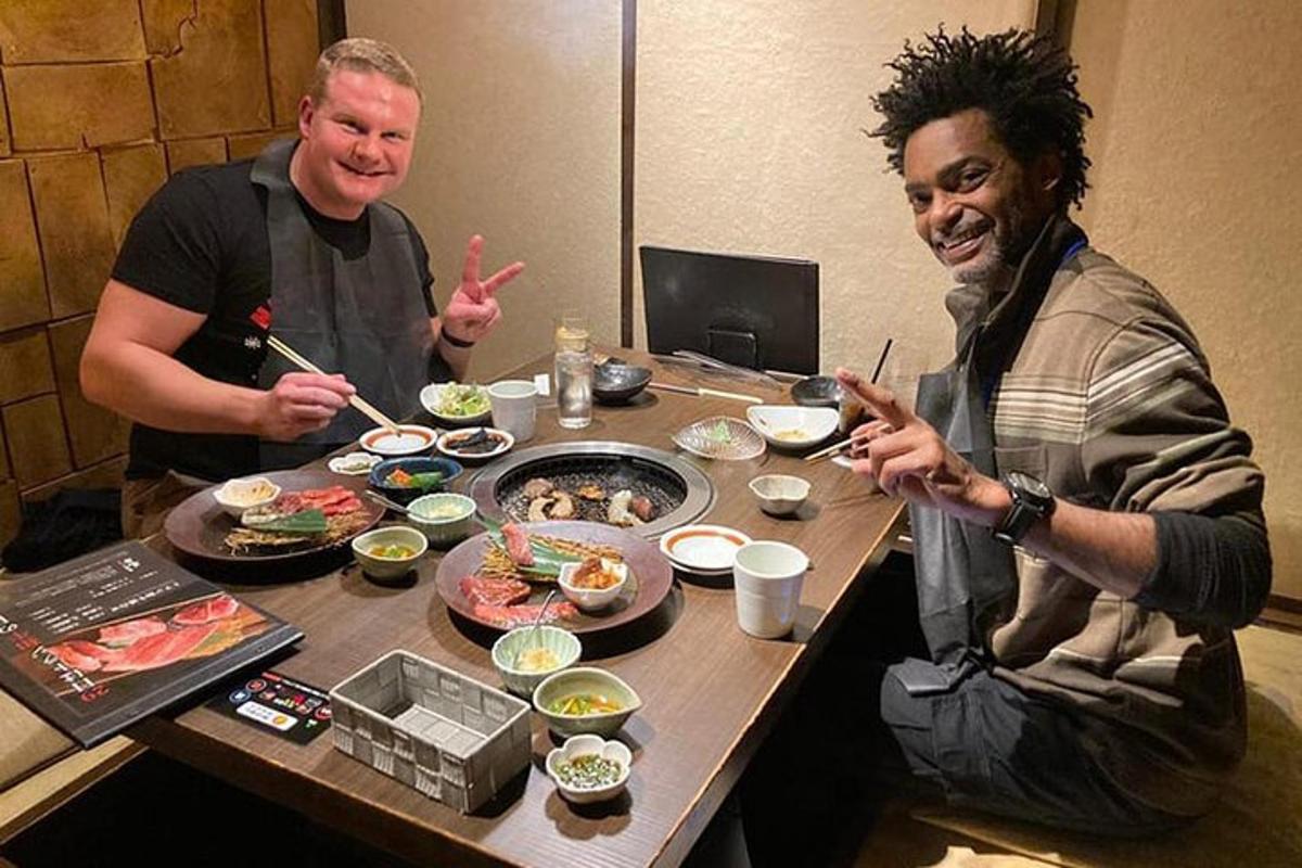 zwei Männer sitzen an einem Tisch und essen mit Stäbchen