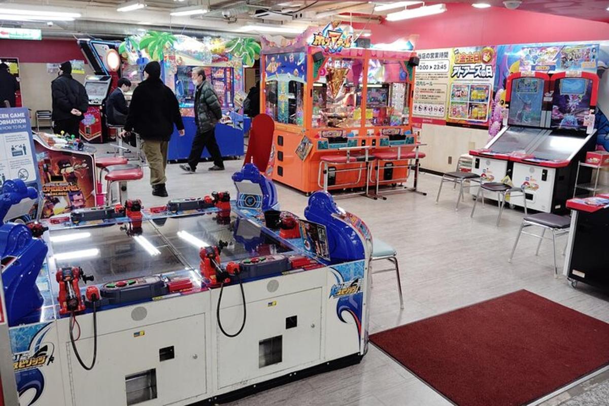 Una sala con juegos de arcade y gente jugando a un videojuego.