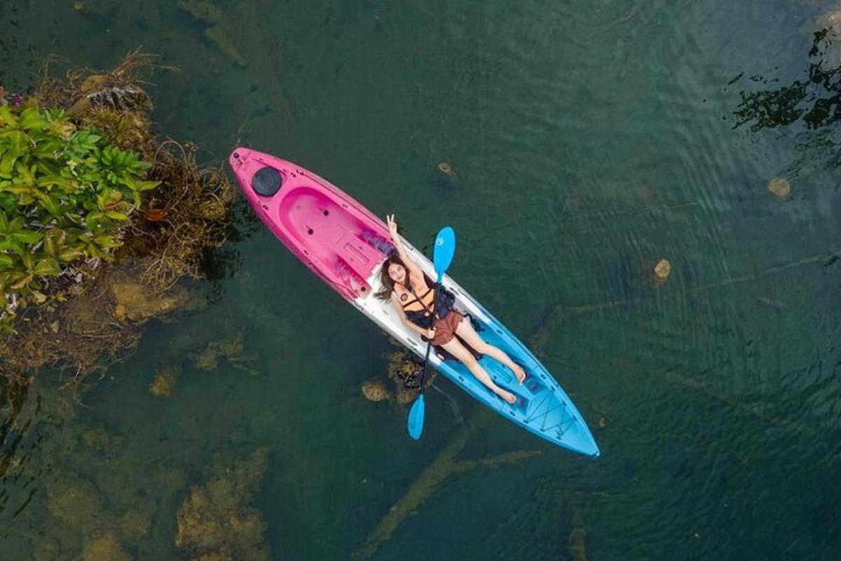 một người phụ nữ nằm trên chiếc thuyền kayak màu hồng dưới nước