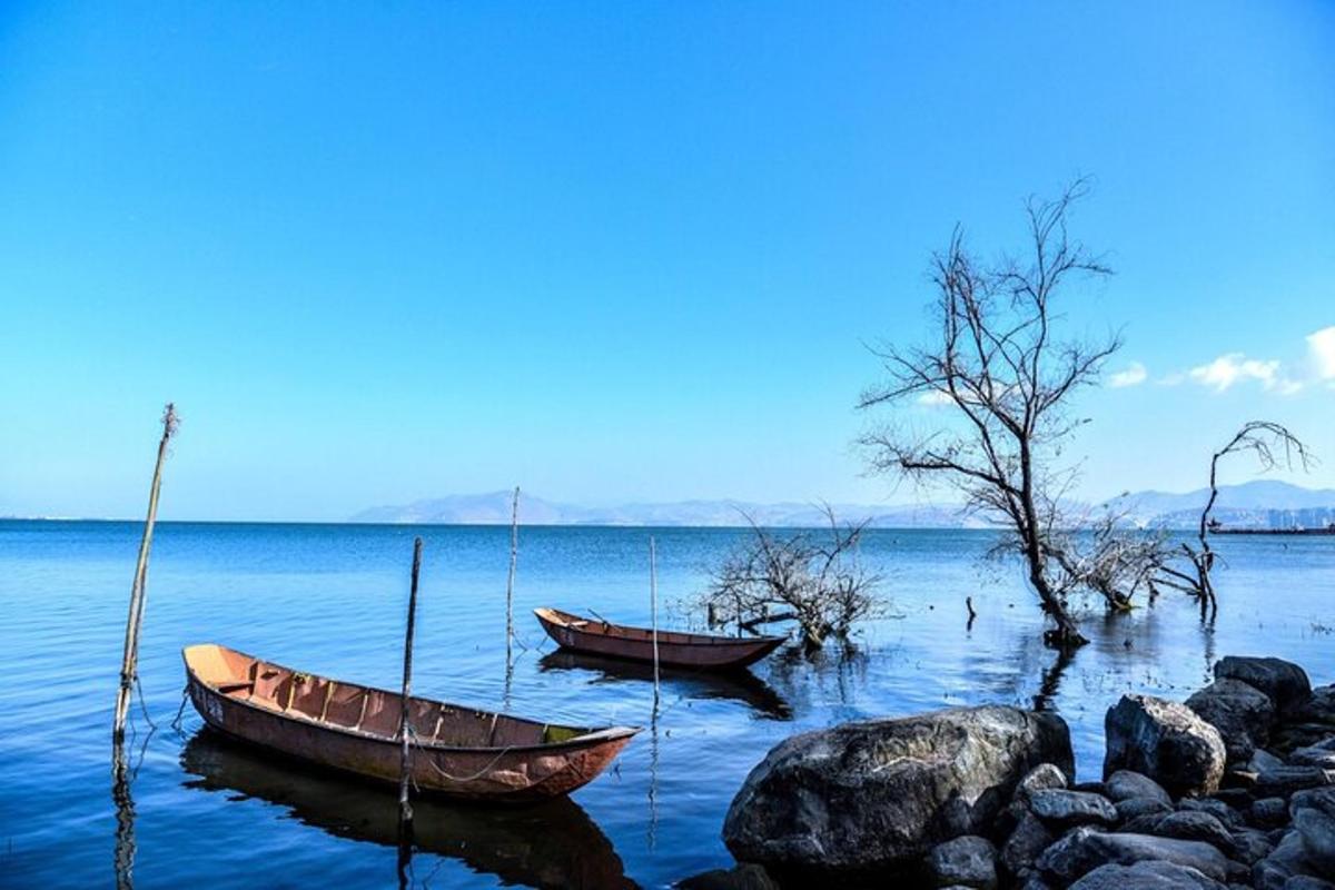 два чамца седе на води близу неких стена