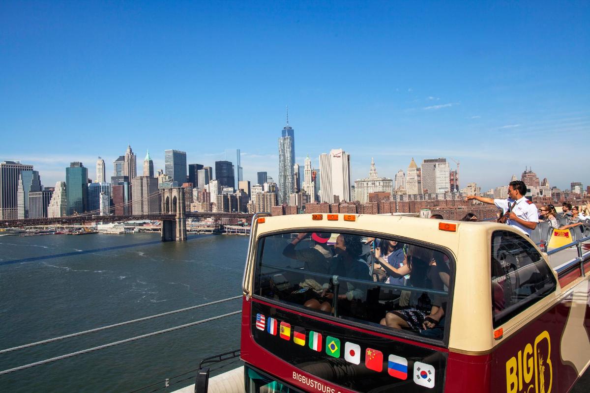 a bus driving down a river next to a city