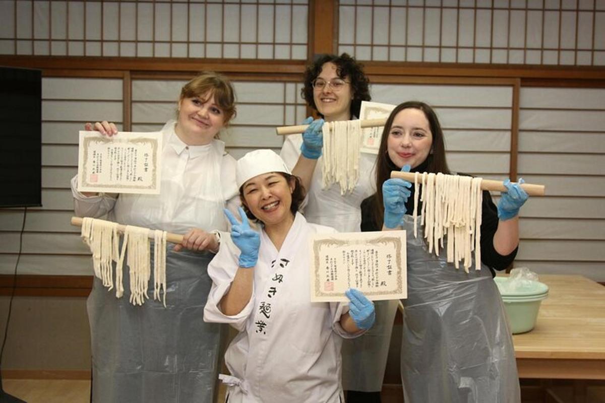a group of women holding up chopsticks of noodles