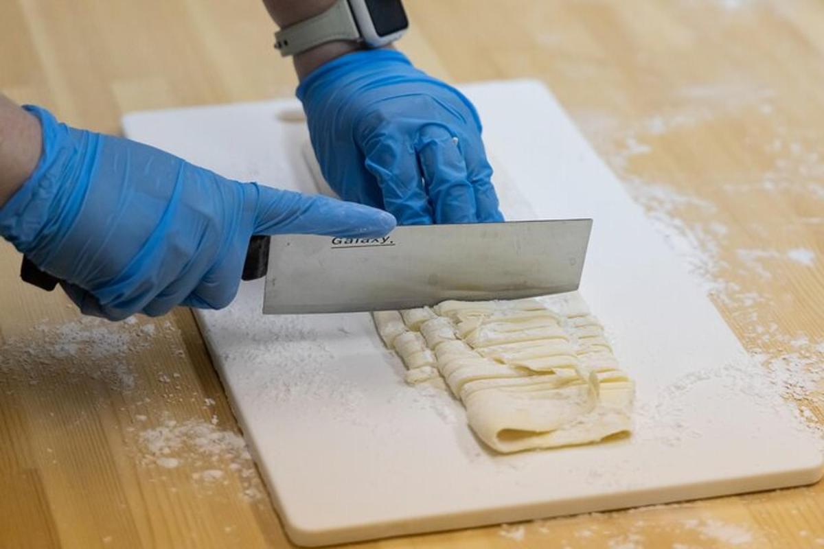 a person in blue gloves holding a knife on a cutting board
