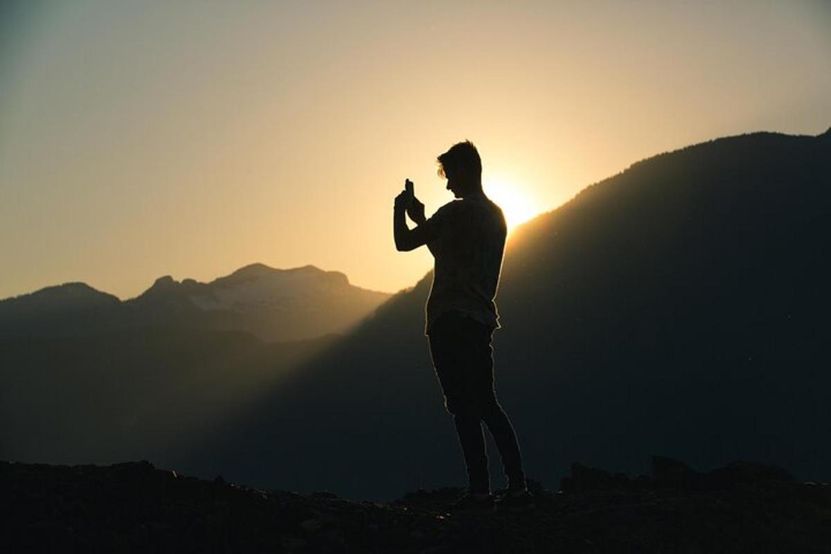 un home dret al cim d'una muntanya a la posta de sol