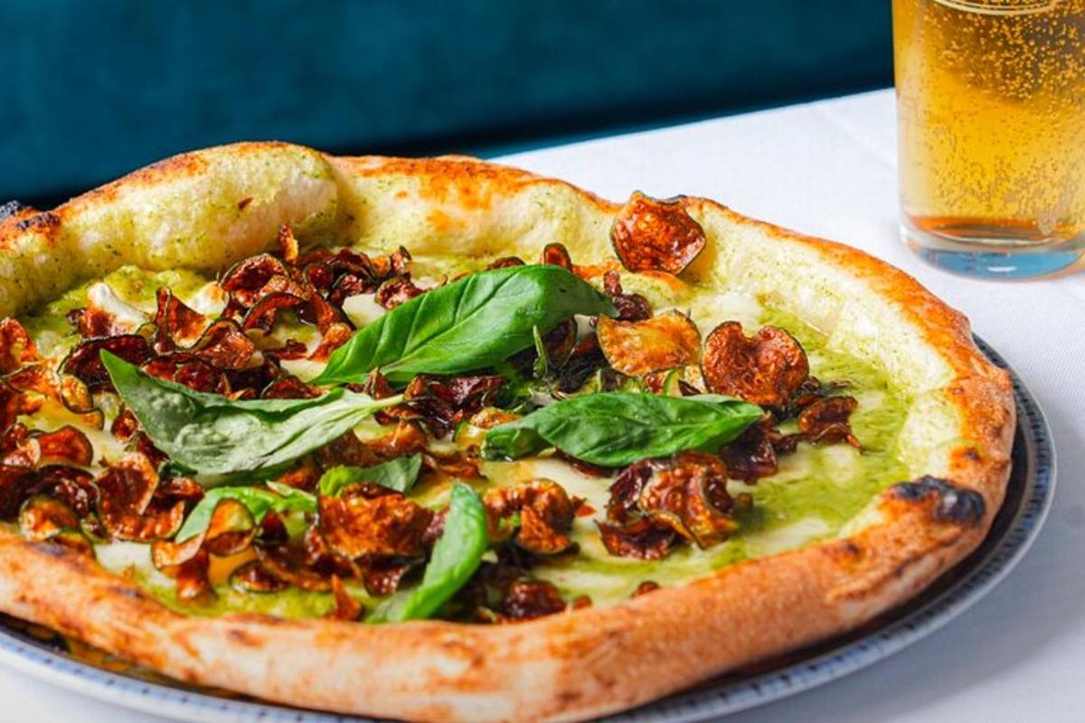 pizza na talíři na stole se sklenicí piva