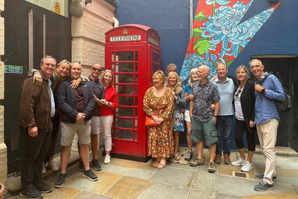 un gruppo di persone in piedi accanto a una cabina telefonica rossa