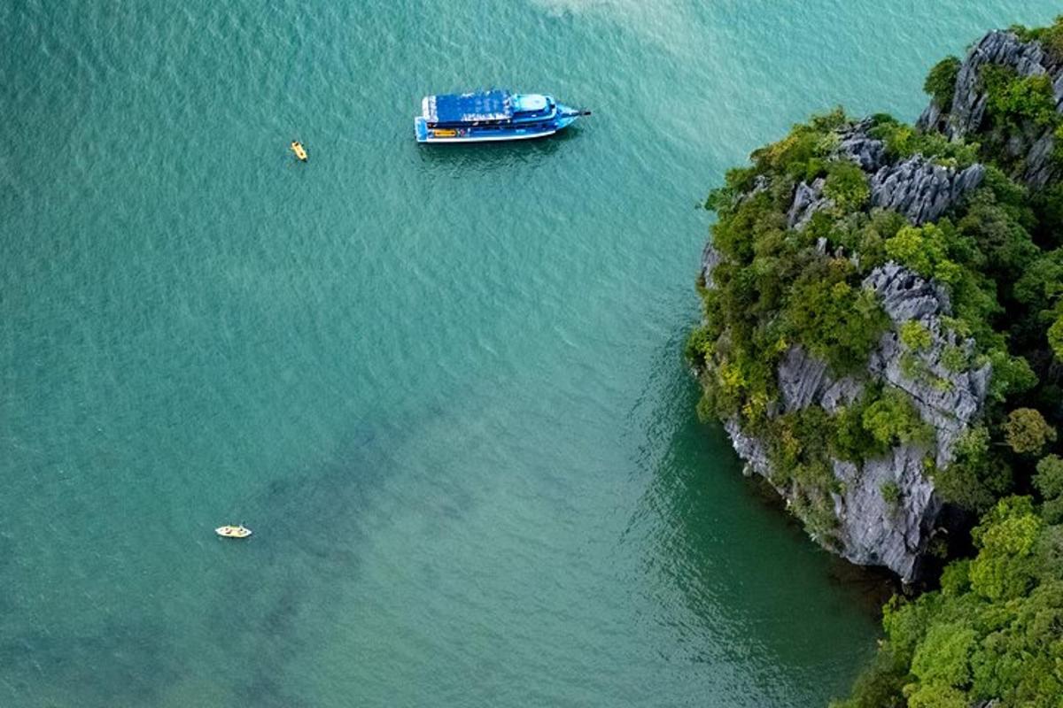 a blue boat in the water next to a cliff