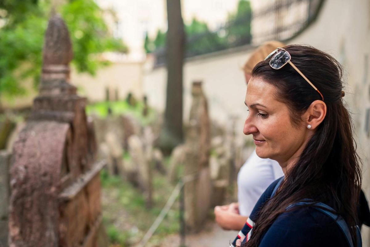eine Frau mit Sonnenbrille auf dem Kopf, die einen Friedhof betrachtet